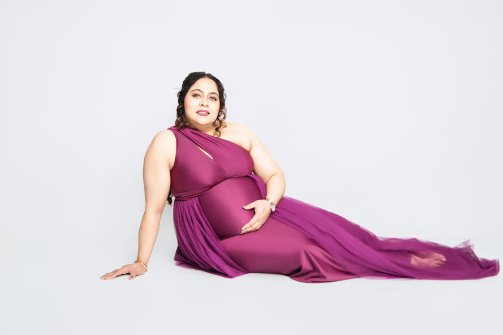 Mother-to-be posing in couture maternity gown in studio
