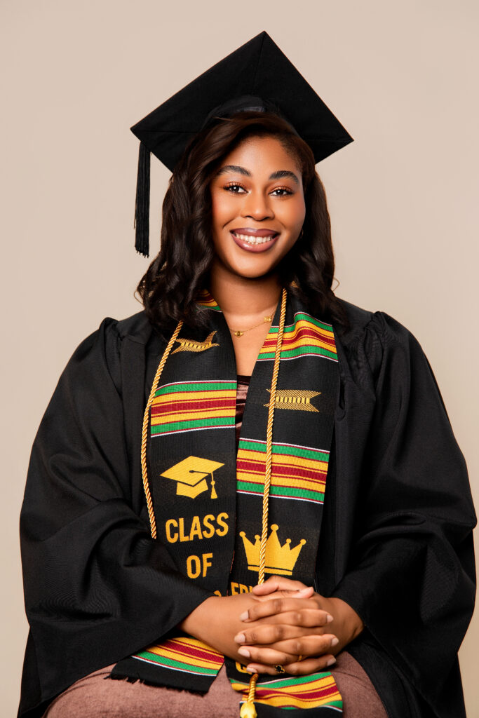 Graduate in cap and gown standing confidently during studio graduation photography session