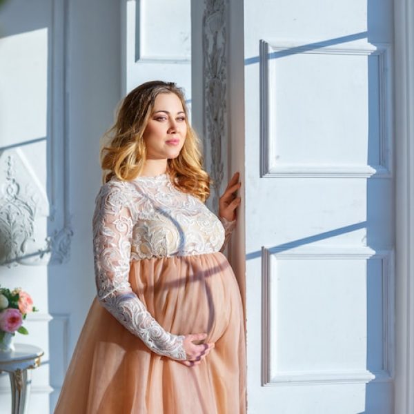pregnant-woman-near-window-beautiful-dress-maternity_78492-1228